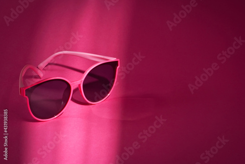 Sunglasses on a pink background. Women's glasses close up. Copy space and place for text near the glasses.