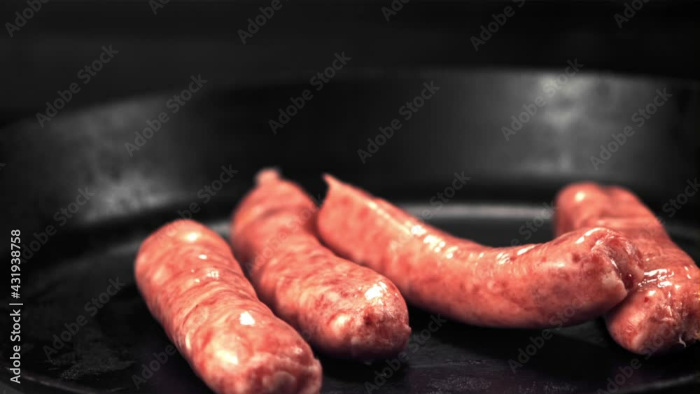 Super slow motion raw sausages fall on the pan. On a black background.Filmed on a high-speed camera at 1000 fps.