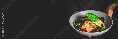 chef in a black suit holds in his hands bowl with salad on Dark grey black background