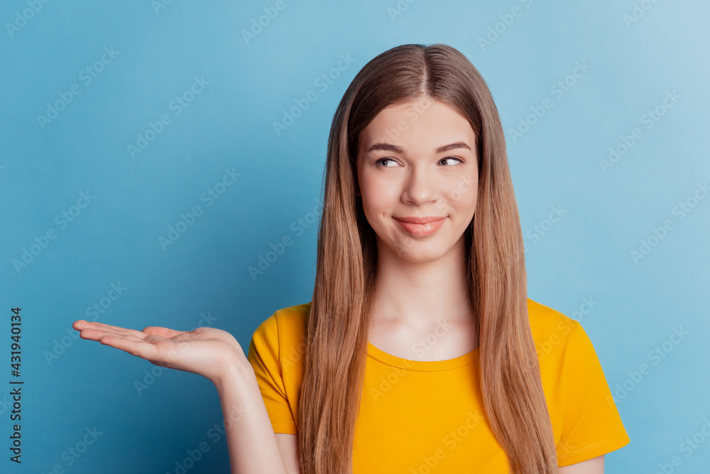 Young woman isolated blue background holding copyspace imaginary on the palm look side Young woman isolated blue background holding copyspace imaginary on the palm look side