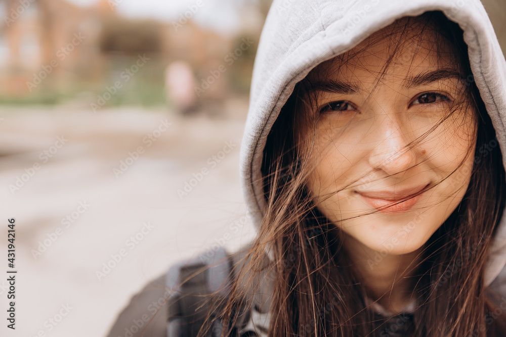 authentic portrait of a girl wearing a hooded jacket with her hair fluttering in the street authentic portrait of a girl wearing a hooded jacket with her hair fluttering in the street