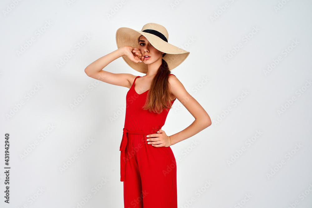 Beautiful girl in sun hat standing on white background in studio in elegant red overall Beautiful girl in sun hat standing on white background in studio in elegant red overall