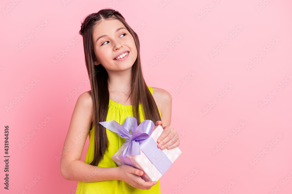 Photo of sweet pretty small schoolgirl dressed yellow outfit holding present box looking empty space smiling isolated pink color background Photo of sweet pretty small schoolgirl dressed yellow outfit holding present box looking empty space smiling isolated pink color background