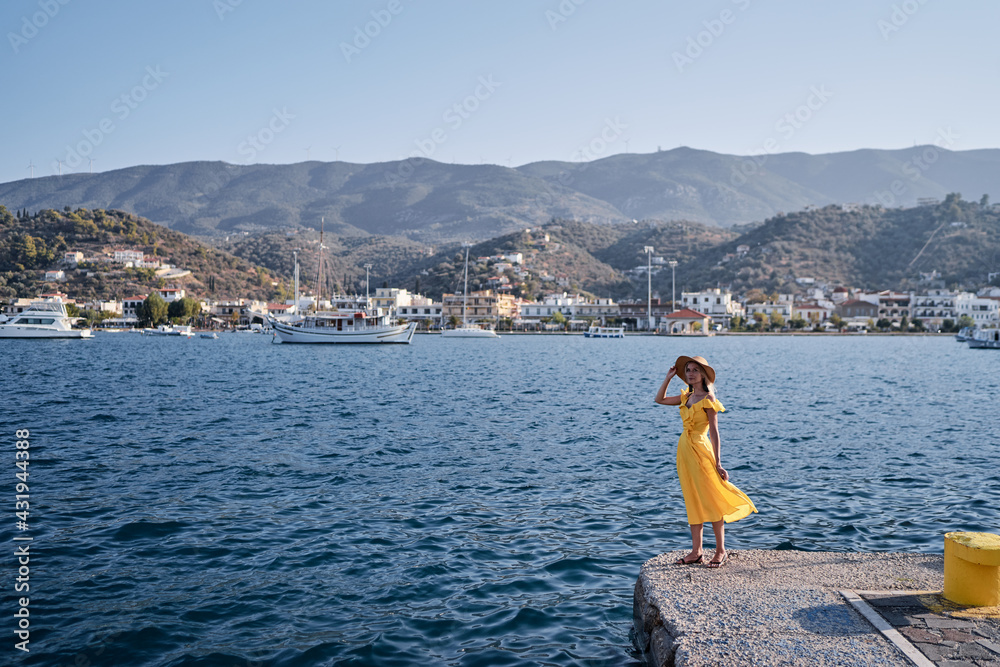 Traveling by Greece. Young happy woman enjoying the view of Poros bay on the sea promenade.