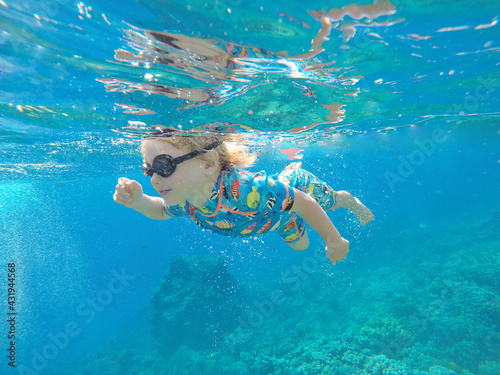 One toddler boy caucasian blond hair snorkeling under sea water. blue sea corals small boy swimming. Summer vacation, outdoor activities, sport, happy holidays, love nature, child nature concept.
