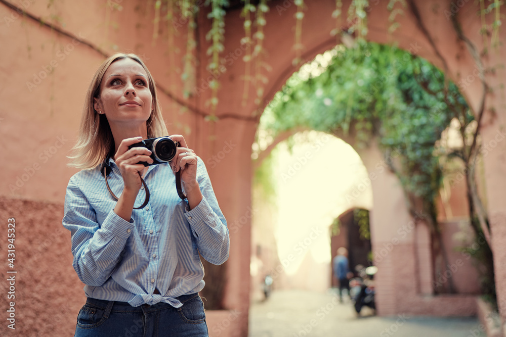 Tourism and technology. Happy young woman taking photo of  Marrakesh old town. Traveling by Morocco.