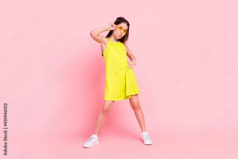 Full length photo of shiny cute school girl wear yellow dress dark eyewear sending you kiss dancing isolated pink color background Full length photo of shiny cute school girl wear yellow dress dark eyewear sending you kiss dancing isolated pink color background