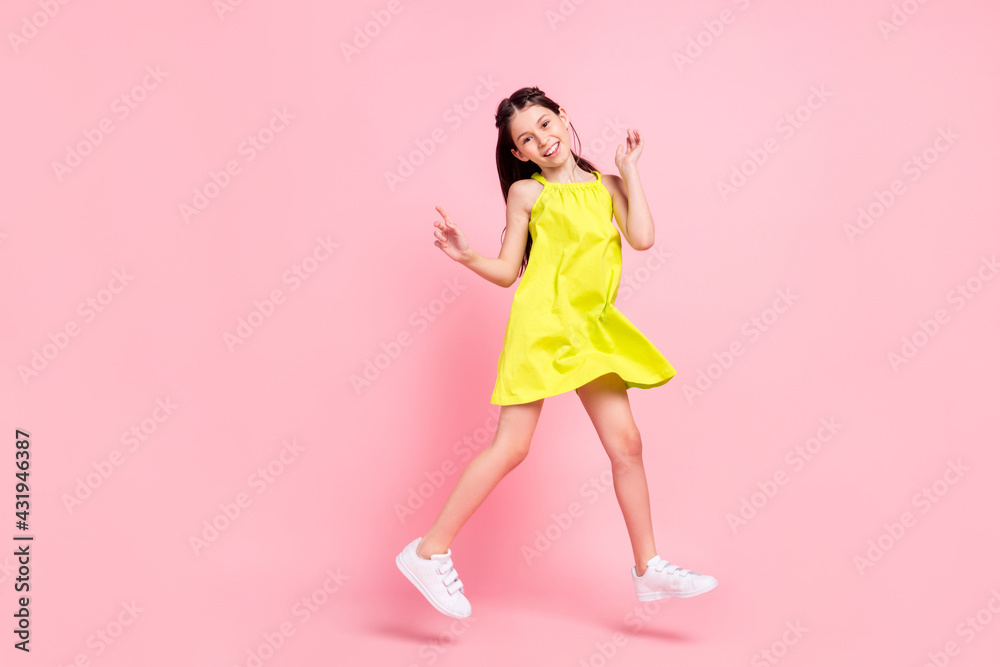 Full length photo of charming sweet school girl wear yellow dress eyewear jumping pointing empty space isolated pink color background Full length photo of charming sweet school girl wear yellow dress eyewear jumping pointing empty space isolated pink color background