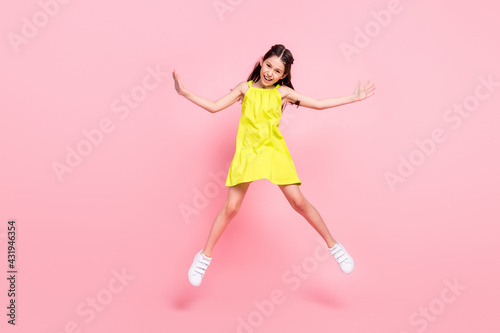 Full length photo of adorable pretty schoolgirl dressed yellow outfit dark glasses jumping high smiling isolated pink color background © deagreez