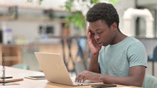 Stressed Young African Man with Laptop having Headache