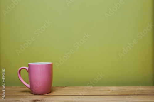 A pink cup of coffee on wooden table