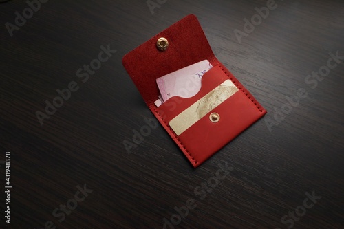 Leather red purse with money and a bank card. Wallet on a dark background
