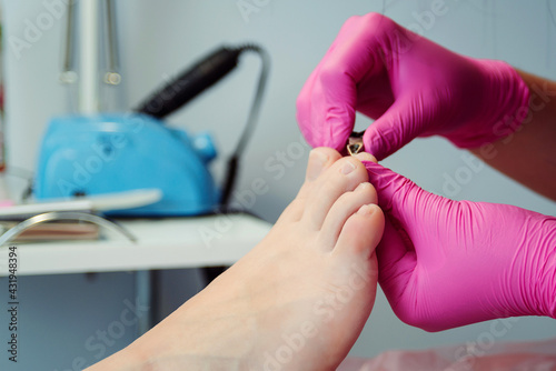 Pedicure master cuts toenails during pedicure procedure. Professional pedicure in the beauty salon.