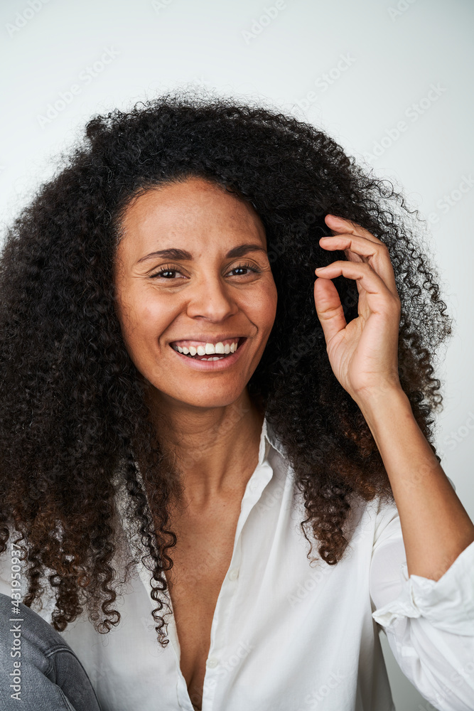 Happy woman with hand in hair over gray background Happy woman with hand in hair over gray background