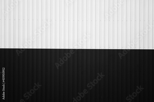 Black and white corrugated iron sheet used as a facade of a warehouse or factory. Texture of a seamless corrugated zinc sheet metal aluminum facade. Architecture. Metal texture.