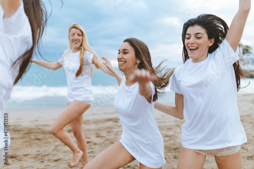 Carefree female friends with arms outstretched enjoying at beach during vacations