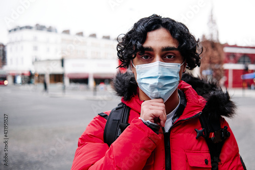 Young man in padded jacket wearing protective face mask during COVID-19 photo