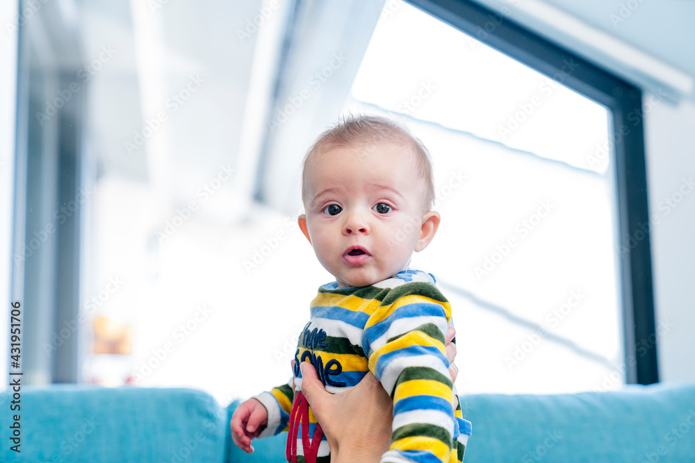 Mother holding cute baby son against window at home Mother holding cute baby son against window at home
