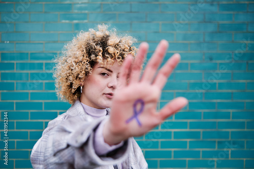 Curly haired woman showing colon cancer ribbon symbol on hand photo