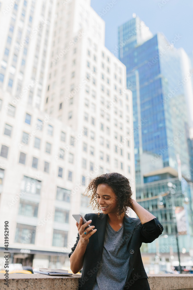 Afro female entrepreneur using smart phone in front of office buildings in city Afro female entrepreneur using smart phone in front of office buildings in city