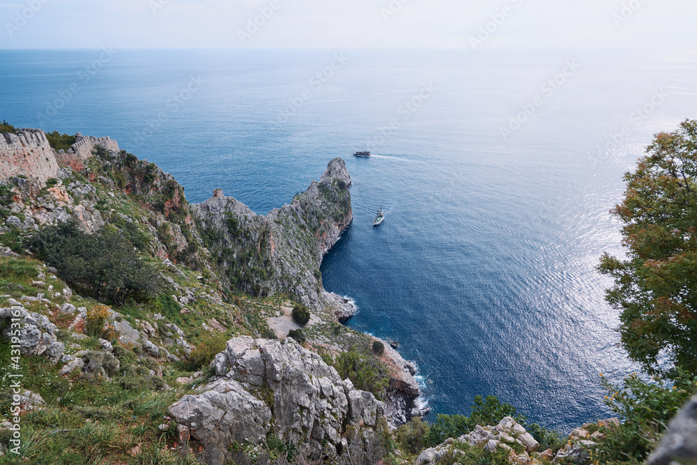 Beautiful landscape with rock cape and ship sailing sea. Alanya, Turkey.