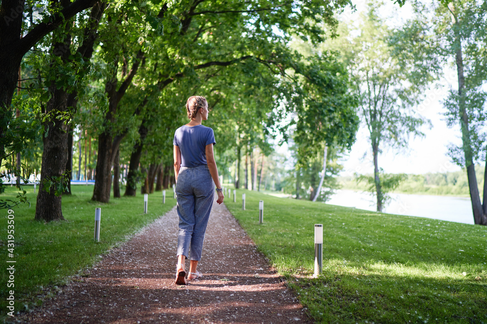 Young woman walking in green summer park. Young woman walking in green summer park.