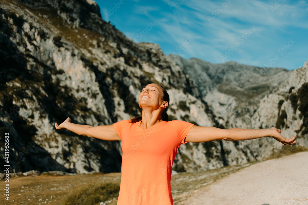 Smiling woman standing with arms outstretched at Cares Trail in Picos De Europe National Park, Asturias, Spain Smiling woman standing with arms outstretched at Cares Trail in Picos De Europe National Park, Asturias, Spain