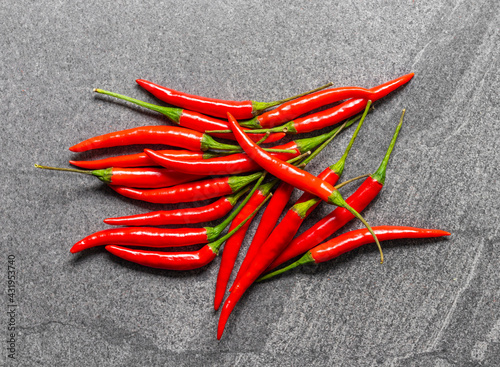 Several fresh Red hot chili pepper on a dark black stone background, food ingredient concept, top view.
