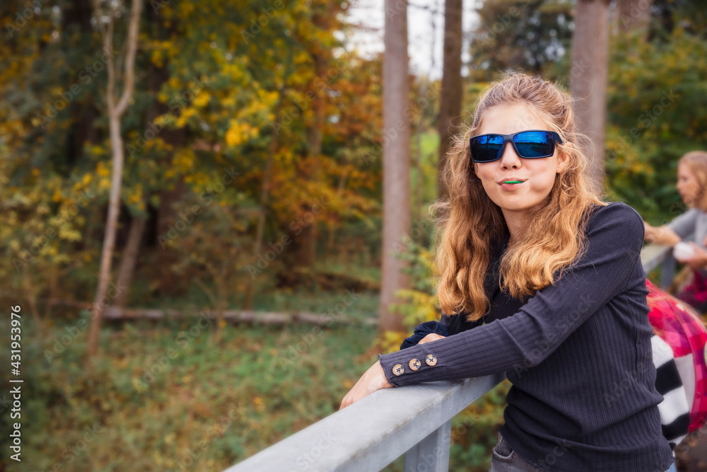 Girl wearing sunglasses smiling while standing by railing Girl wearing sunglasses smiling while standing by railing