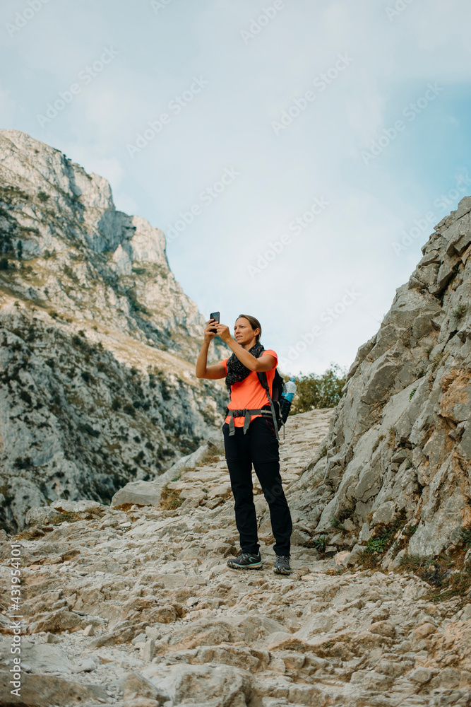 Woman explorer using mobile phone while standing at Cares Trail in Picos De Europe National Park, Asturias, Spain Woman explorer using mobile phone while standing at Cares Trail in Picos De Europe National Park, Asturias, Spain