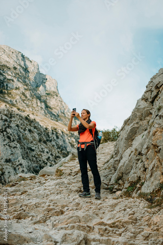Woman explorer using mobile phone while standing at Cares Trail in Picos De Europe National Park, Asturias, Spain photo