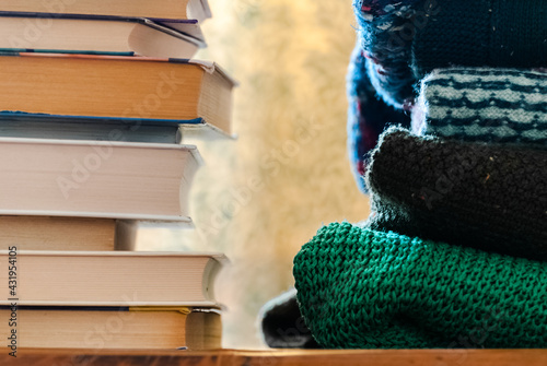 Stacks of books and sweaters on the shelf.