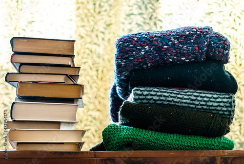 Stacks of books and sweaters on the shelf.