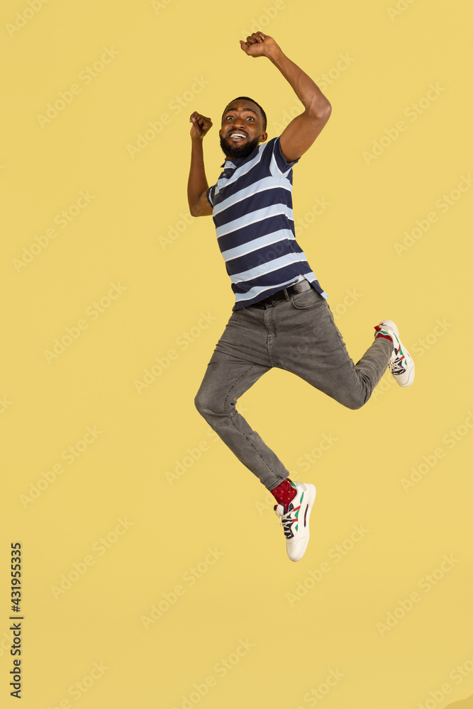 One African young man jumping isolated over yellow studio background with copyspace for ad