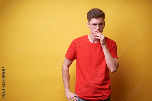 Think about solutions. Colorful studio portrait of thoughtful young man in red t-shirt on yellow background.