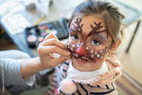 Cute girl with painted face at home during Christmas photo