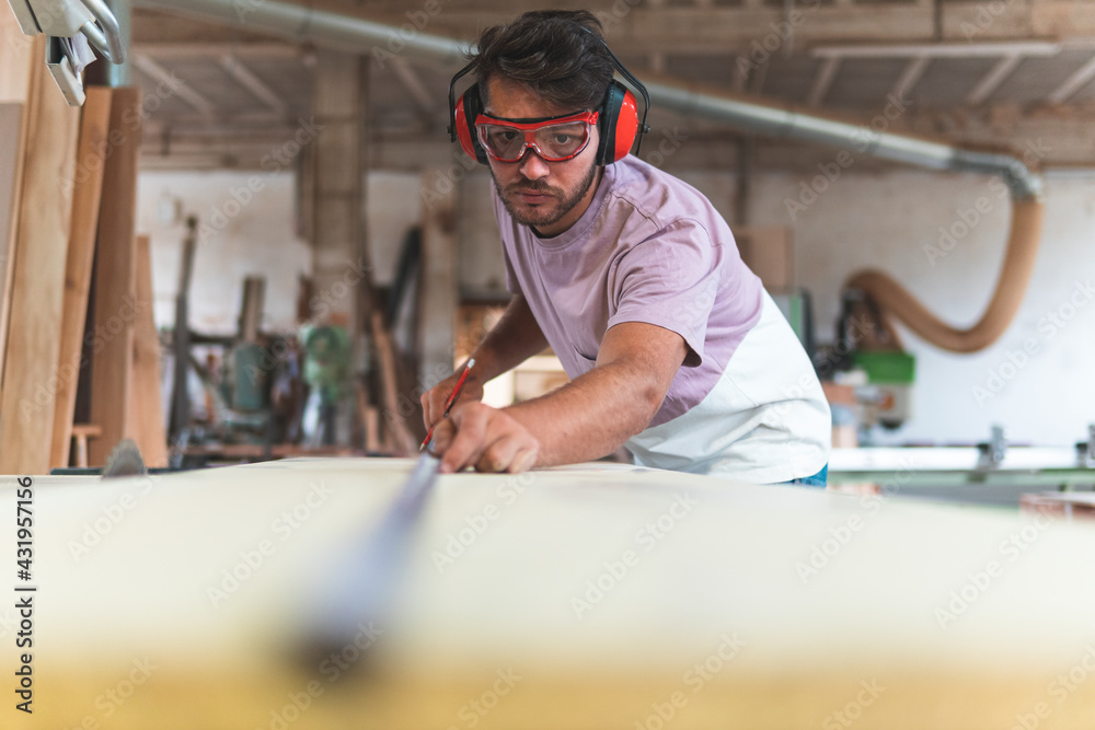 Male carpenter using tape measure while working in workshop Male carpenter using tape measure while working in workshop
