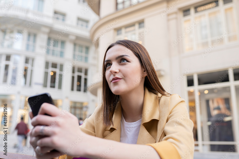 Beautiful woman with smart phone looking away in city Beautiful woman with smart phone looking away in city