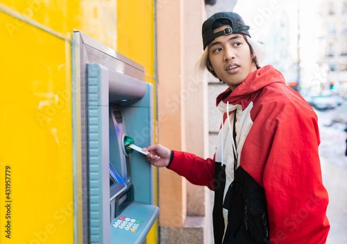 Asian man withdrawing money from ATM machine