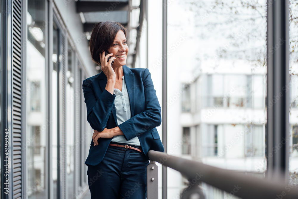© Joseffson/Westend61 - Happy businesswoman talking on mobile phone on office balcony © Joseffson/Westend61 - Happy businesswoman talking on mobile phone on office balcony