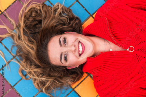 Happy woman lying on multi colored tiled floor