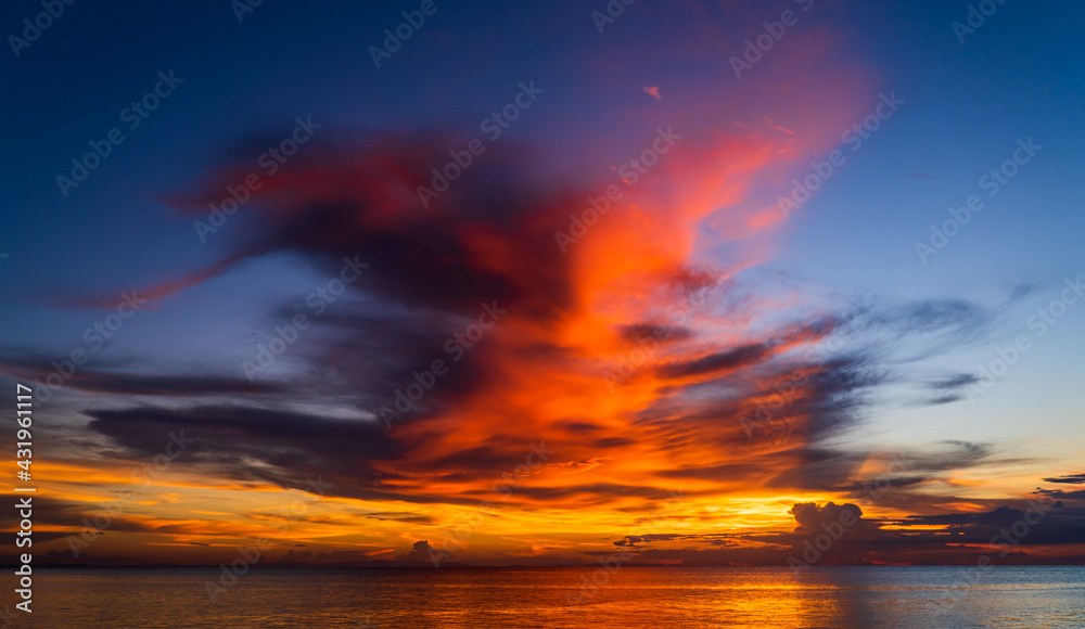 Sunset sky over sea in the evening on twilight with majestic orange sunlight clouds after sundown, Dusk sky background 