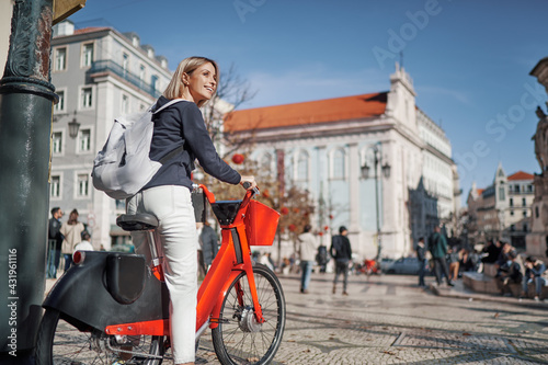 Cycling and tourism. Pretty young woman riding bicycle by Lisbon, Portugal.