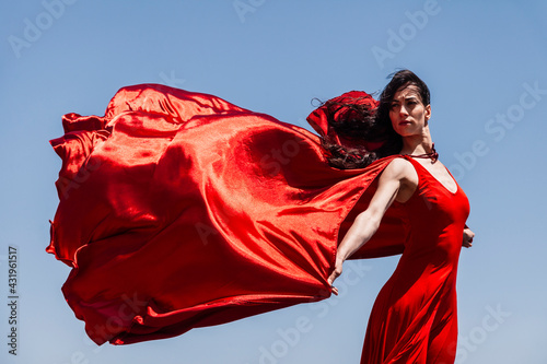 Beautiful female dancer with red scarf looking away against clear sky on sunny day photo