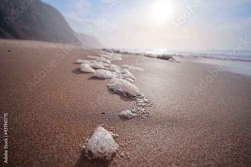 Sea foam on the beautiful sand Atlantic ocean beach.