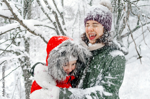 Cheerful teenage girl embracing sister while snowing during vacations