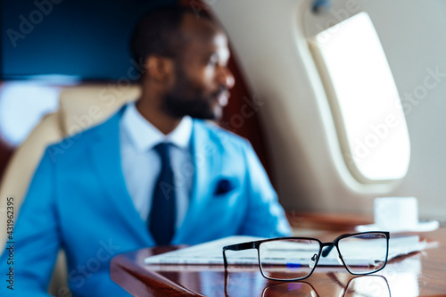 businessman with eyeglasses and newspaper on table in private jet photo