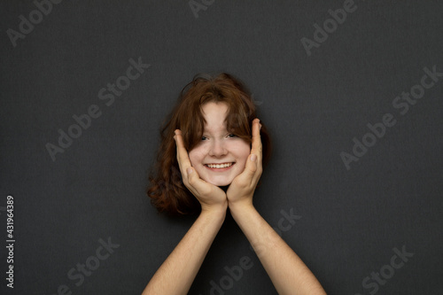 Studio shot of head of teenage girl leaning on male hands