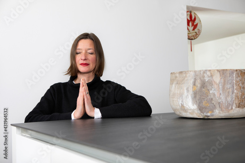Woman with eyes closed praying at home photo