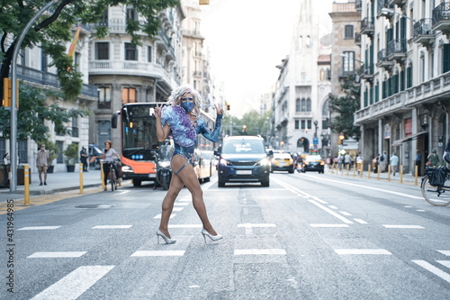 Drag queen gesturing peace sign while crossing street in city photo